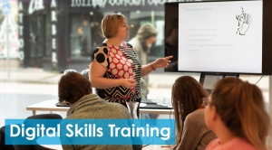 Photo of a woman presenting to a group of people with text overlay 'Digital Skills Training'
