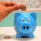 A hand putting a coin into a blue piggy bank