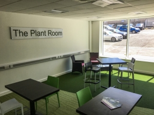 Office space with a sign on the wall saying 'The Plant Room'