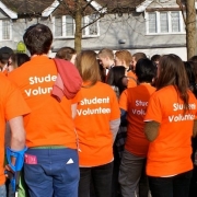 Group of people wearing orange t-shirts with 'Student Volunteer' on the back