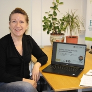 Photo of a woman sat at a desk in front of a laptop showing free recruitment toolkit